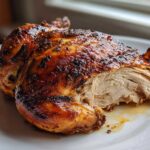 Close-up of a perfectly cooked air fryer whole chicken, showing crispy skin and moist, shredded white meat.