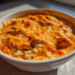 Close-up of creamy, cheesy, orange buffalo chicken dip served hot in a white bowl.
