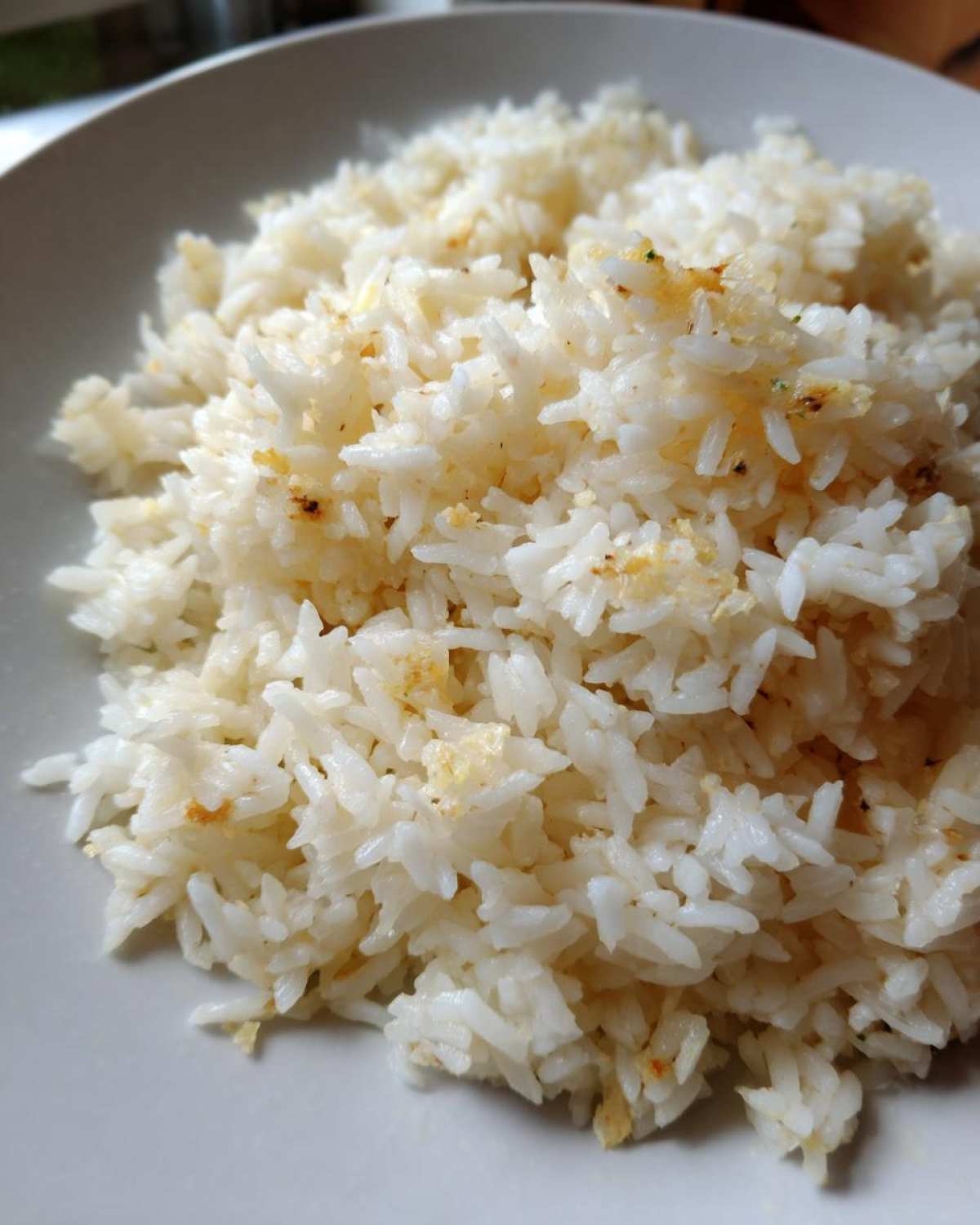 Close-up of fluffy white butter rice seasoned with golden specks, served in a light gray bowl.