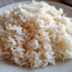 Close-up of fluffy, perfectly cooked butter rice piled high on a light-colored plate.