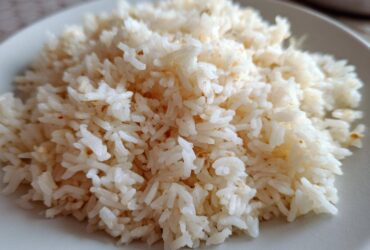 Close-up of fluffy, perfectly cooked butter rice piled high on a light-colored plate.