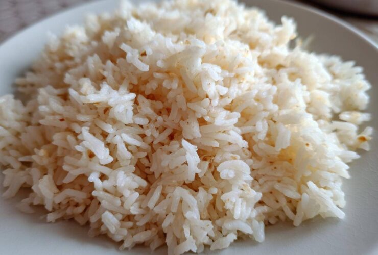 Close-up of fluffy, perfectly cooked butter rice piled high on a light-colored plate.