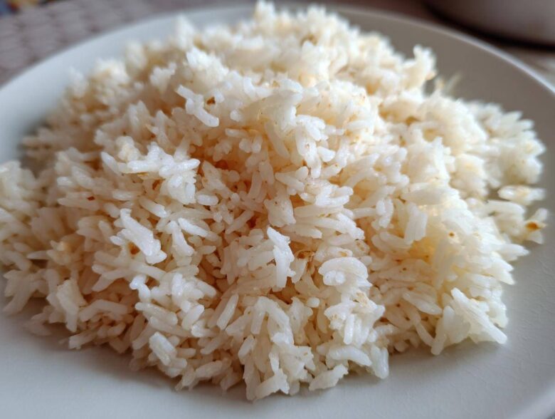 Close-up of fluffy, perfectly cooked butter rice piled high on a light-colored plate.