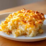 A close-up serving of amazing cheesy potato casserole with a golden, melted cheese topping.