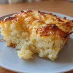 A close-up slice of amazing cheesy potato casserole with a golden-brown, bubbly cheese crust.