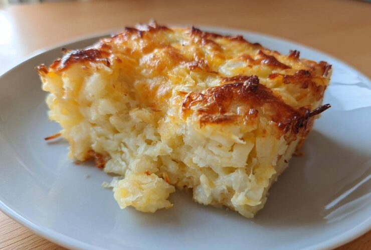 A close-up slice of amazing cheesy potato casserole with a golden-brown, bubbly cheese crust.