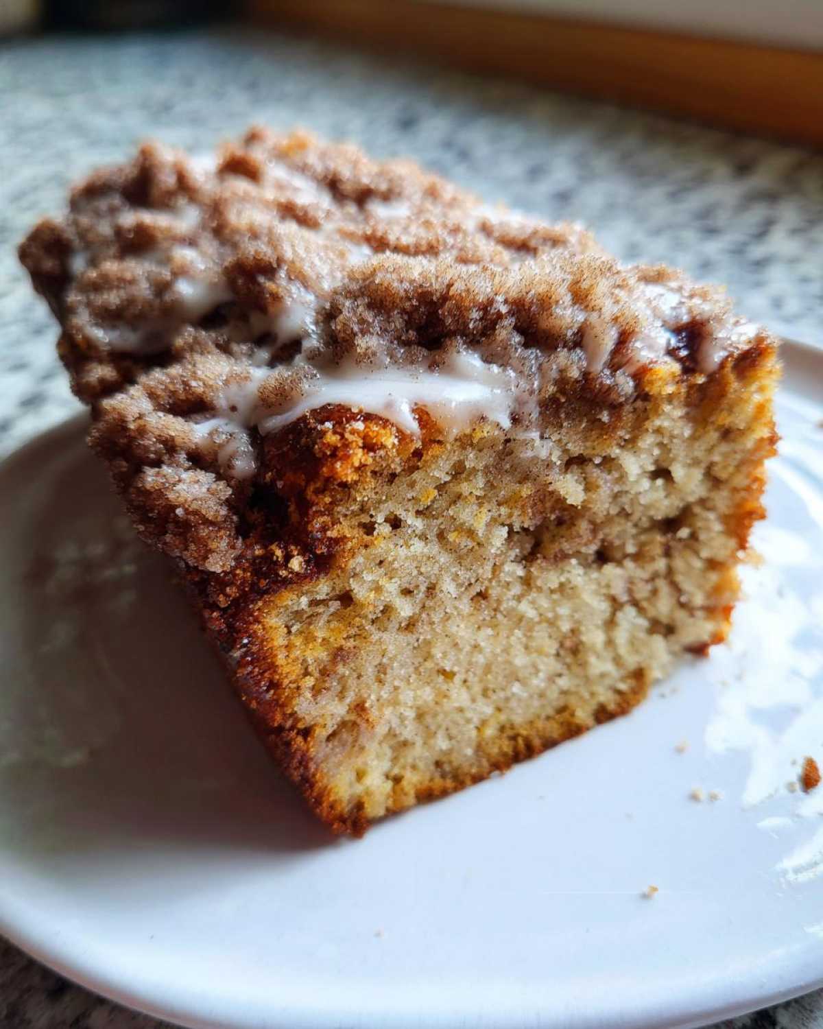 A close-up of a moist slice of amazing coffee cake topped with cinnamon streusel and a vanilla glaze.