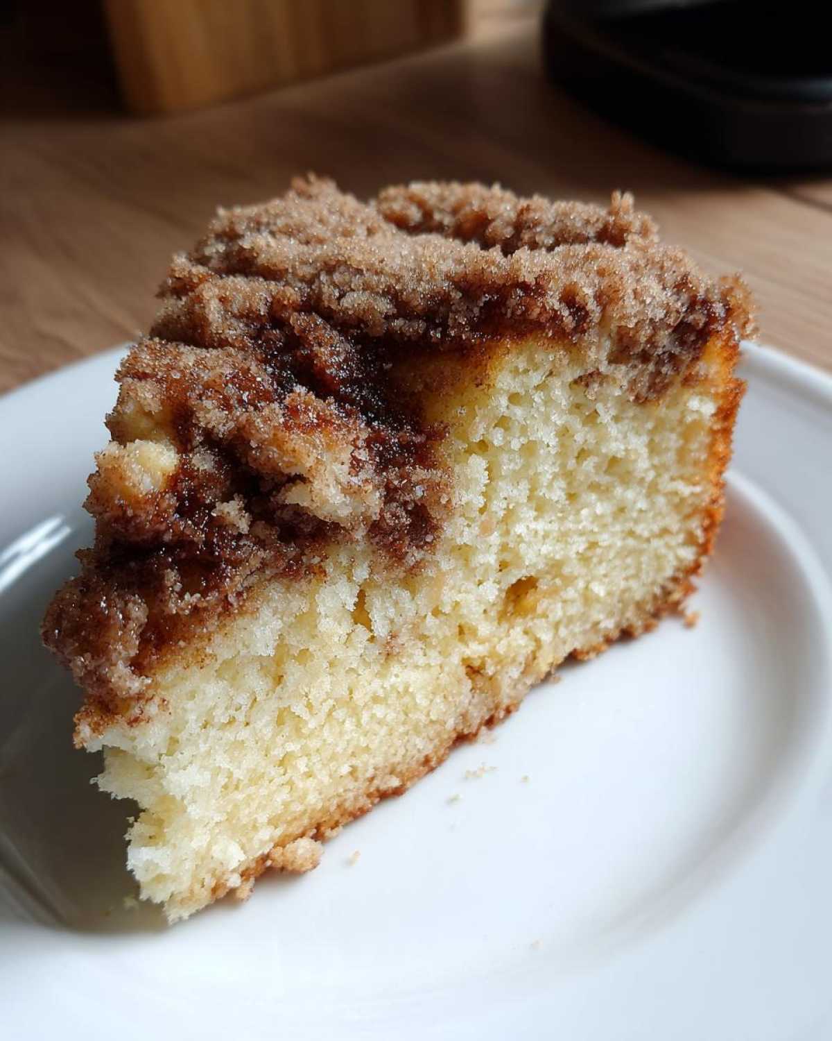 Close-up of a moist slice of coffee cake featuring a thick, sugary cinnamon streusel topping.