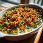 A close-up of a creamy green bean casserole topped generously with crispy fried onions.
