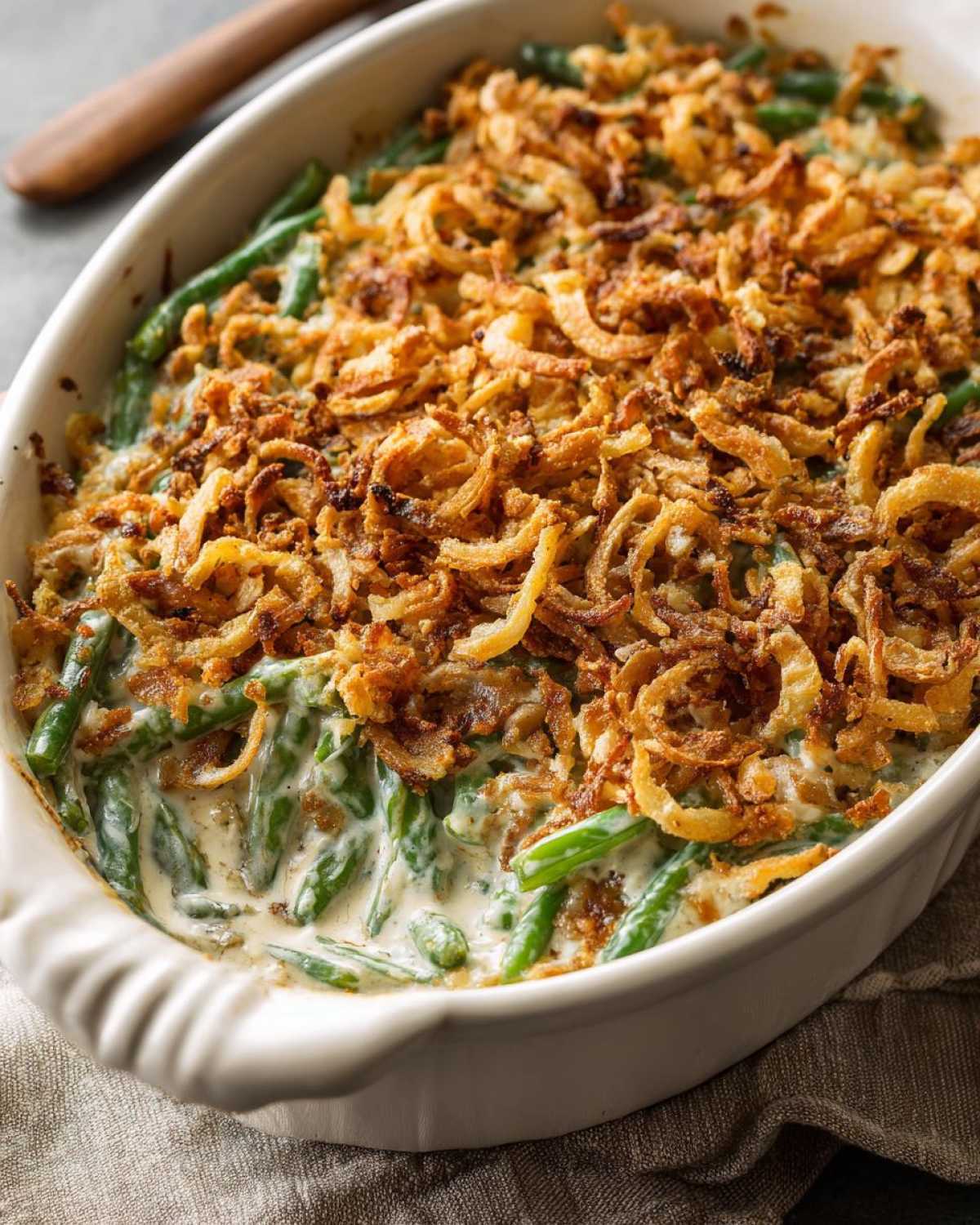 Close-up of creamy green bean casserole topped generously with crispy fried onions.