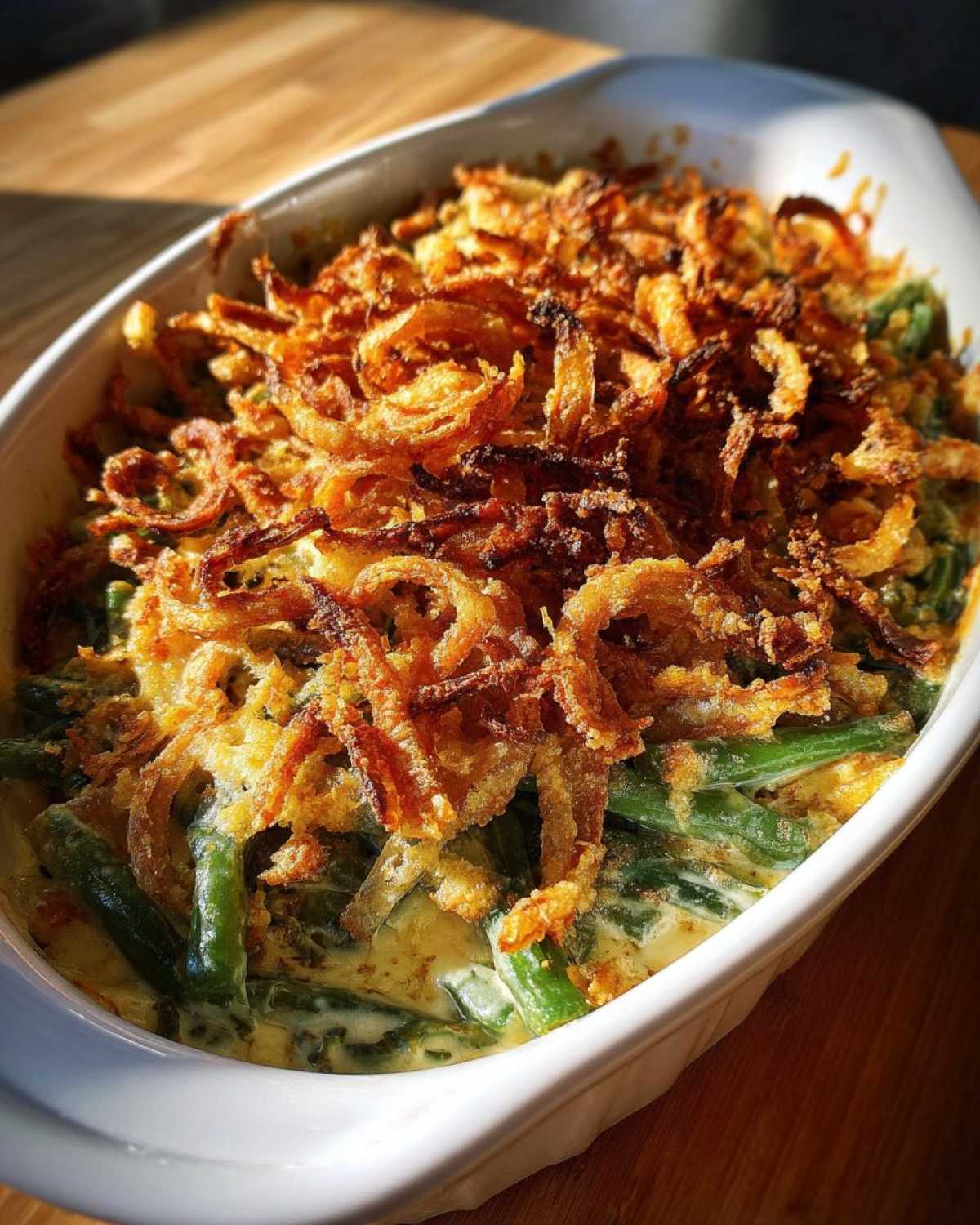 A close-up of a creamy green bean casserole topped generously with crispy fried onions.