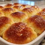 Close-up of a pan of amazing soft dinner rolls with a shiny, golden-brown glaze.