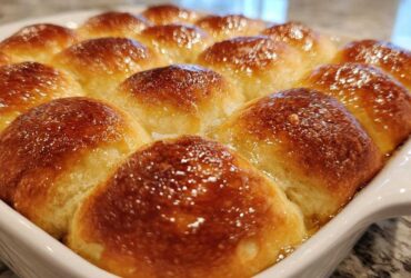 Close-up of a pan of amazing soft dinner rolls with a shiny, golden-brown glaze.