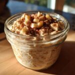 A single jar filled with creamy apple cinnamon overnight oats, topped with diced apples and cinnamon.