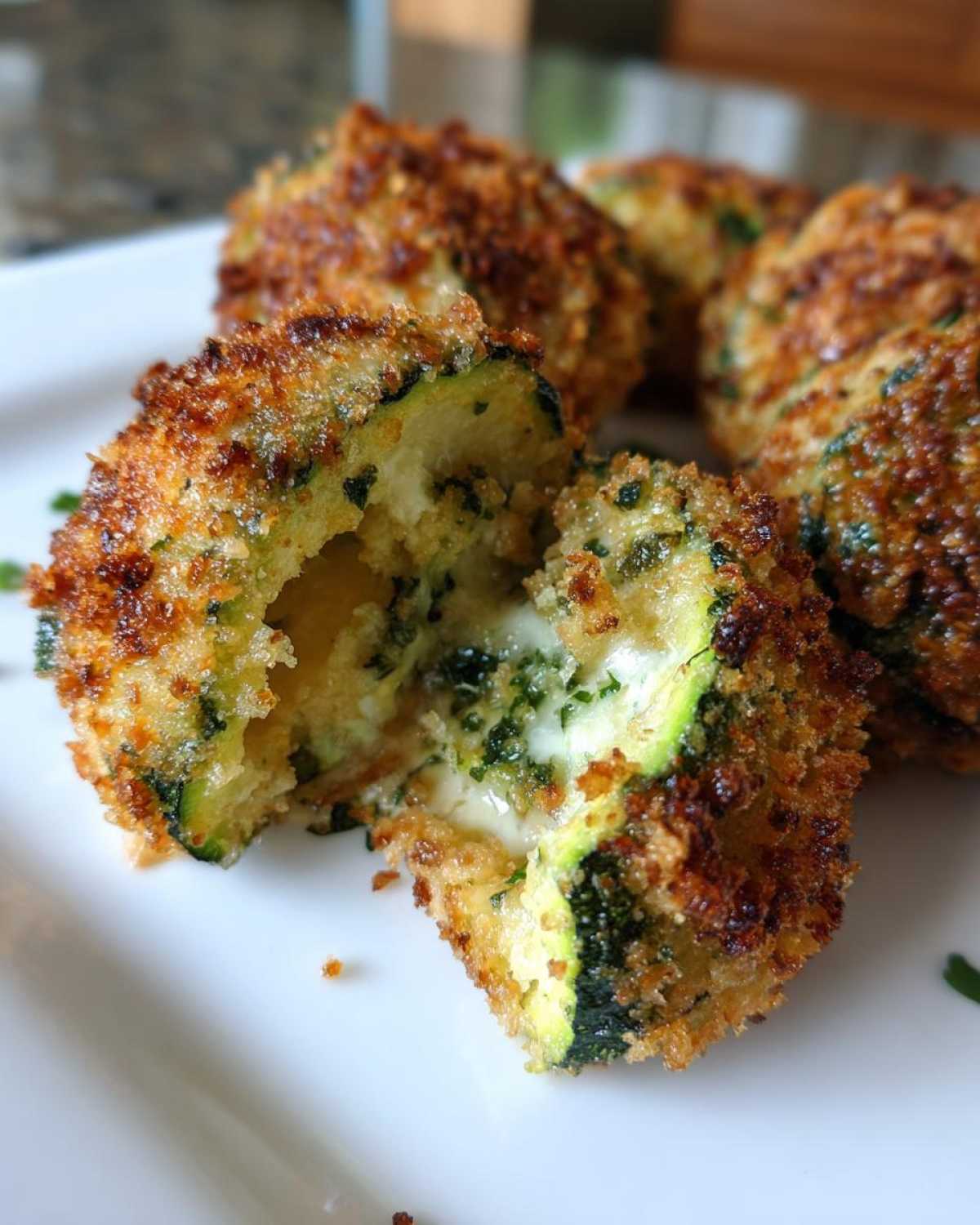Close-up of baked parmesan zucchini cut open showing melted cheese filling and crispy breading.