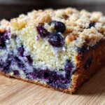 A close-up cross-section of moist blueberry banana bread topped with a crumbly streusel topping.