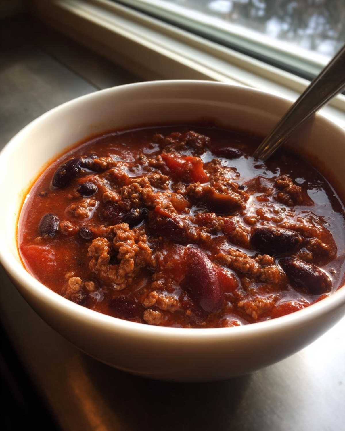 Close-up of a steaming bowl of hearty chili with ground beef and kidney beans, perfect for the best chili recipe.