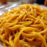 Close-up of spaghetti generously coated in a vibrant, creamy butternut squash pasta sauce.