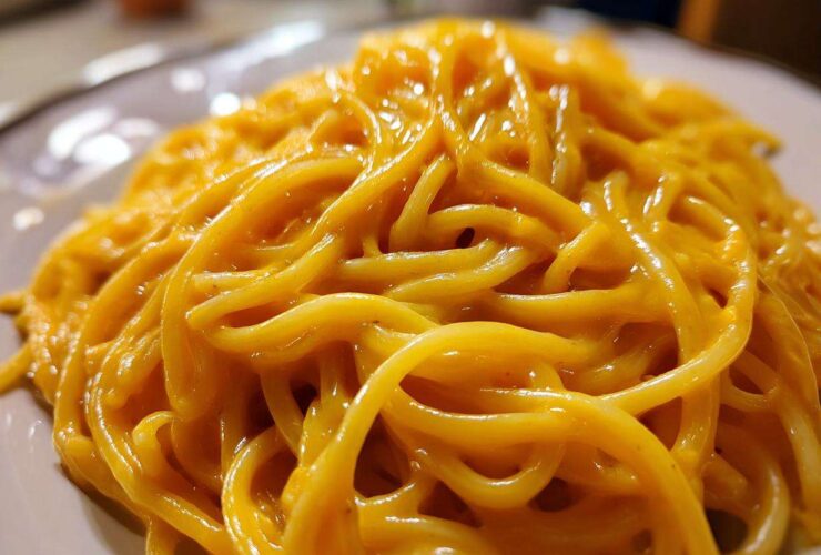 Close-up of spaghetti generously coated in a vibrant, creamy butternut squash pasta sauce.