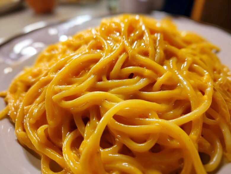 Close-up of spaghetti generously coated in a vibrant, creamy butternut squash pasta sauce.