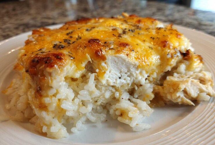 A serving of cheesy chicken and rice casserole showing melted, browned cheese topping over creamy rice and white chicken pieces.