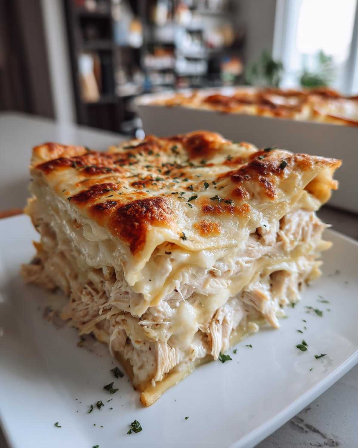 A thick, cheesy slice of chicken alfredo lasagna with layers of shredded chicken and creamy sauce.