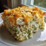 A close-up of a square serving of creamy chicken broccoli rice casserole with a golden, cheesy topping.