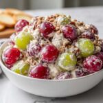 Close-up of creamy chicken salad chick grape salad featuring red and green grapes mixed with a creamy dressing and topped with chopped pecans.