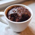 Close-up of a rich, dark chocolate mug cake with melted chocolate chips on top, ready to eat.