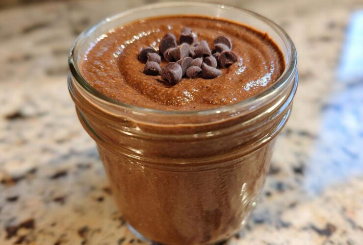 Close-up of creamy chocolate overnight oats topped with mini chocolate chips in a glass jar.