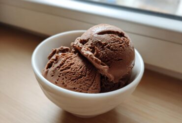 Two scoops of rich chocolate protein ice cream served in a small white bowl.