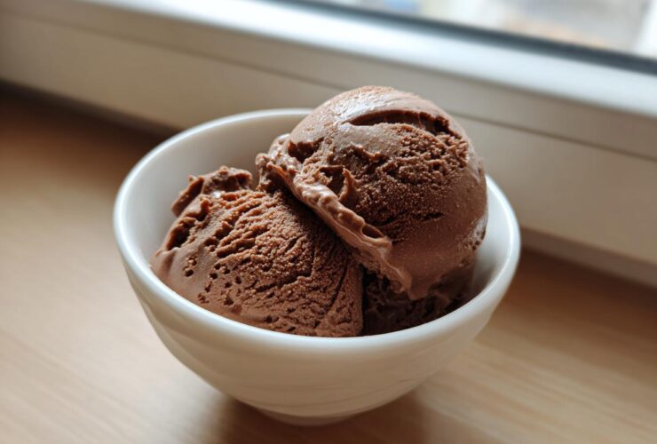 Two scoops of rich chocolate protein ice cream served in a small white bowl.
