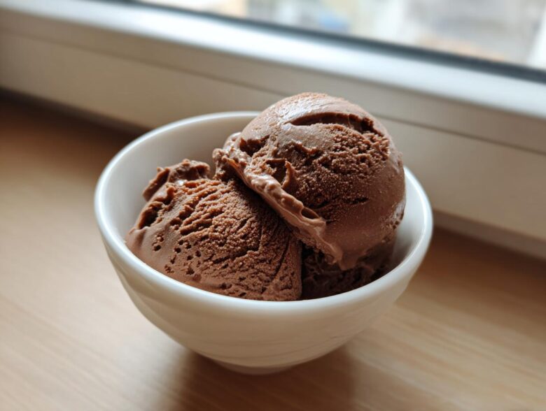 Two scoops of rich chocolate protein ice cream served in a small white bowl.
