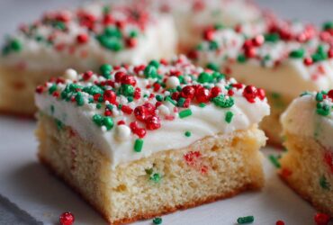 A close-up of a square slice of Christmas sugar cookie bars topped with thick white frosting and red and green holiday sprinkles.