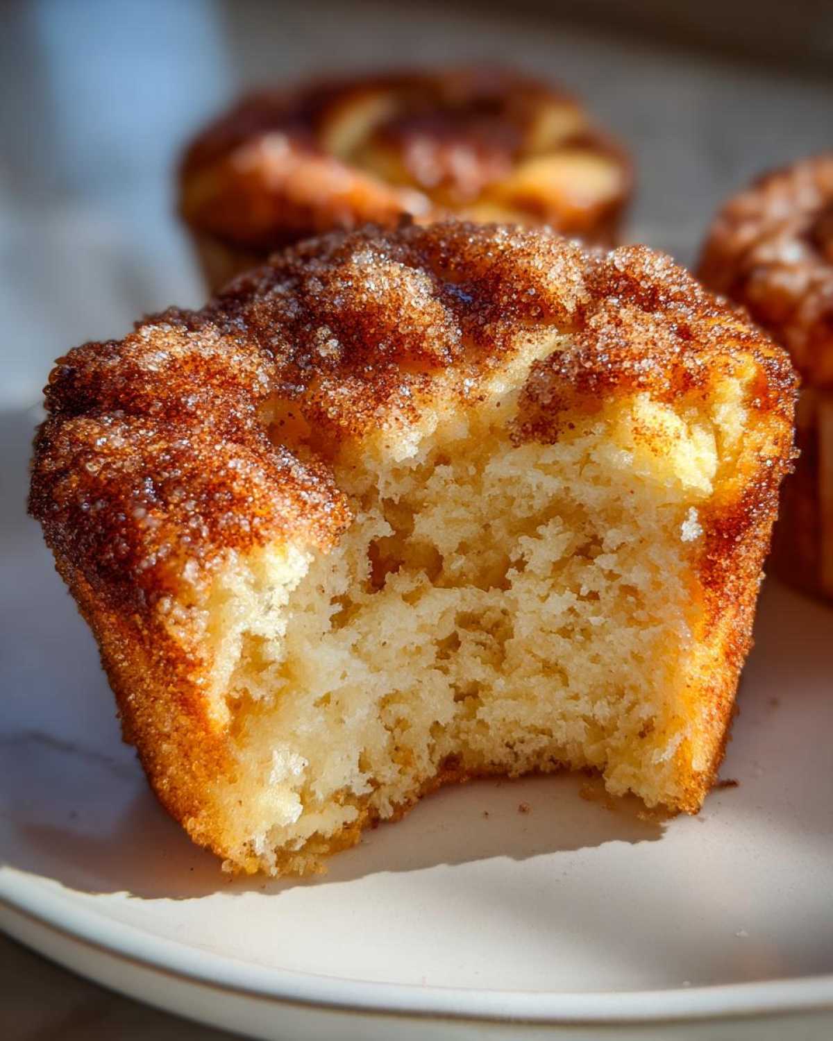Close-up of a cinnamon sugar french toast muffin with a bite taken out, showing the fluffy interior.