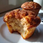 Close-up of a cinnamon sugar french toast muffins with a bite taken out, showing the soft interior.