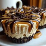 Close-up of a rich cookie butter cheesecake cup topped with caramel, chocolate drizzle, and cookie crumbs.