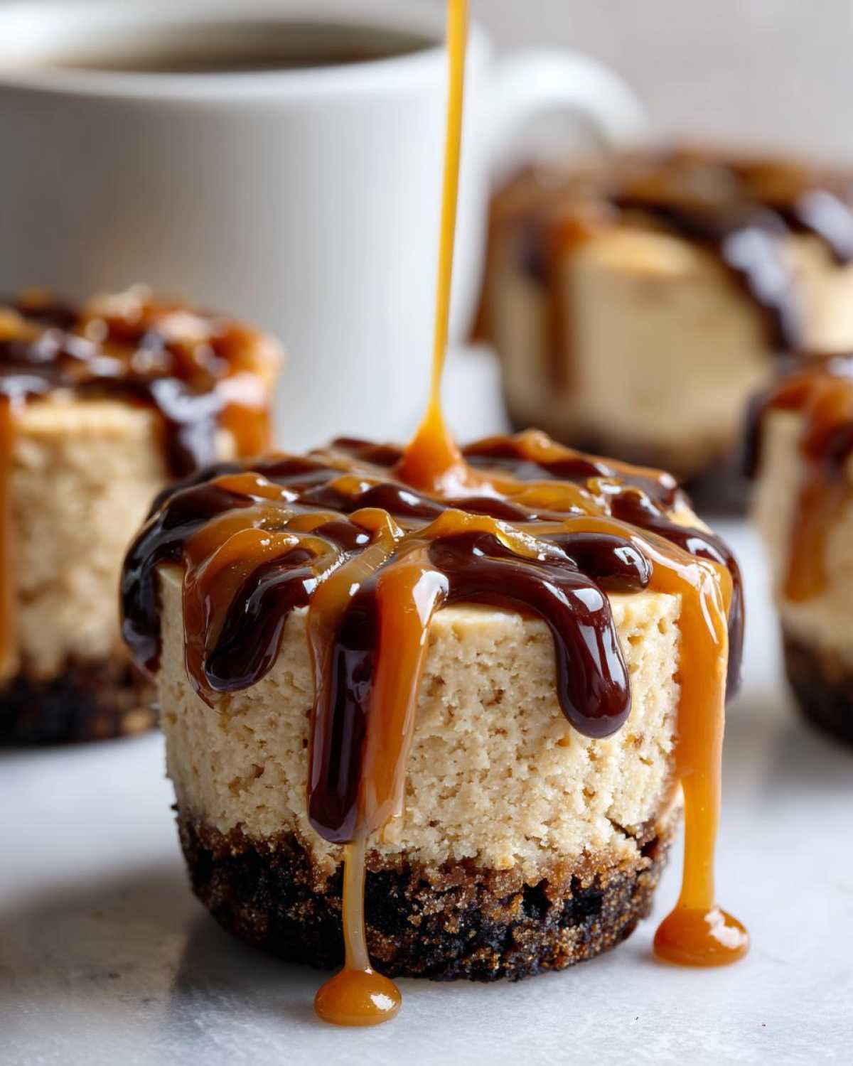 Close-up of a cookie butter cheesecake cup being drizzled with caramel and chocolate sauce.