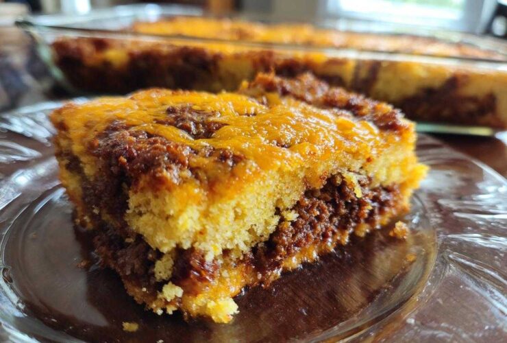 A close-up slice of cowboy cornbread casserole showing layers of cornbread, savory filling, and melted cheddar cheese.