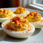 Four beautifully prepared deviled eggs with creamy, piped filling, dusted generously with paprika.