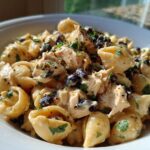Close-up of creamy enchilada pasta featuring shell pasta, shredded chicken, black beans, and parsley garnish.