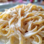 Close-up of fettuccine pasta coated in thick, creamy homemade alfredo sauce.