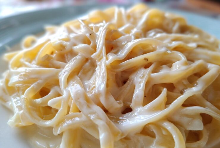 Close-up of fettuccine pasta coated in thick, creamy homemade alfredo sauce.