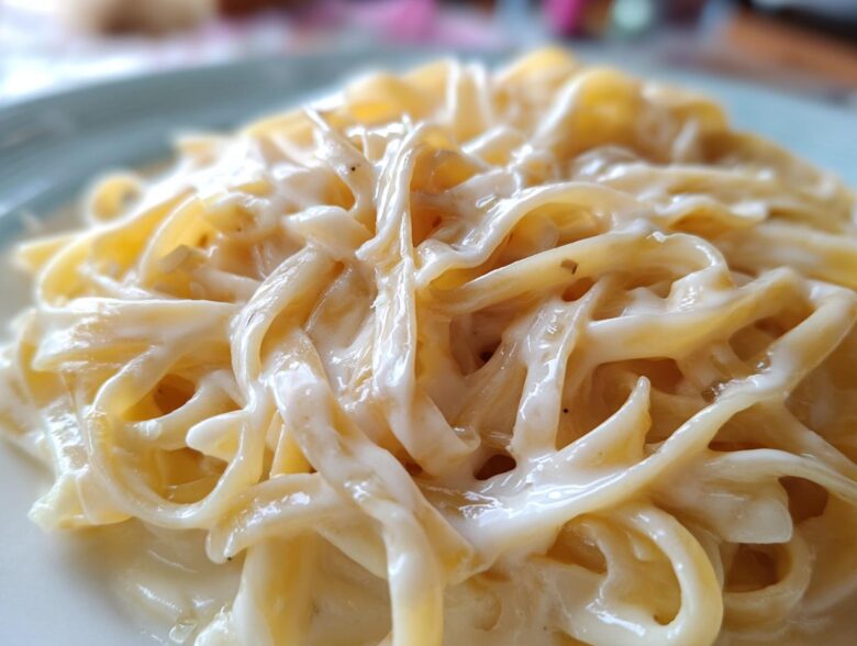 Close-up of fettuccine pasta coated in thick, creamy homemade alfredo sauce.