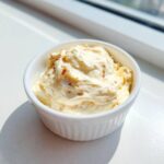 Close-up of creamy homemade garlic aioli with visible flecks, served in a small white ramekin.
