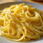 A close-up shot of spaghetti coated in a rich, bright sauce for creamy lemon pasta served on a white plate.