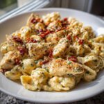 Close-up of creamy marry me chicken pasta featuring shell pasta, seasoned chicken pieces, and sun-dried tomatoes.