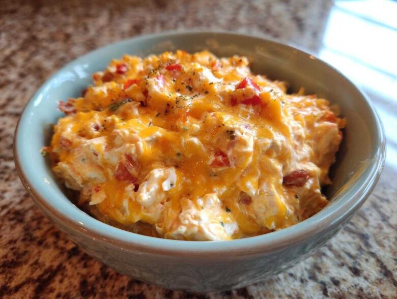 Close-up of creamy, cheesy rotel dip topped with melted cheddar and herbs in a light blue bowl.