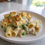 Close-up of creamy tuna pasta made with rigatoni, green peas, and a golden baked cheese crust.
