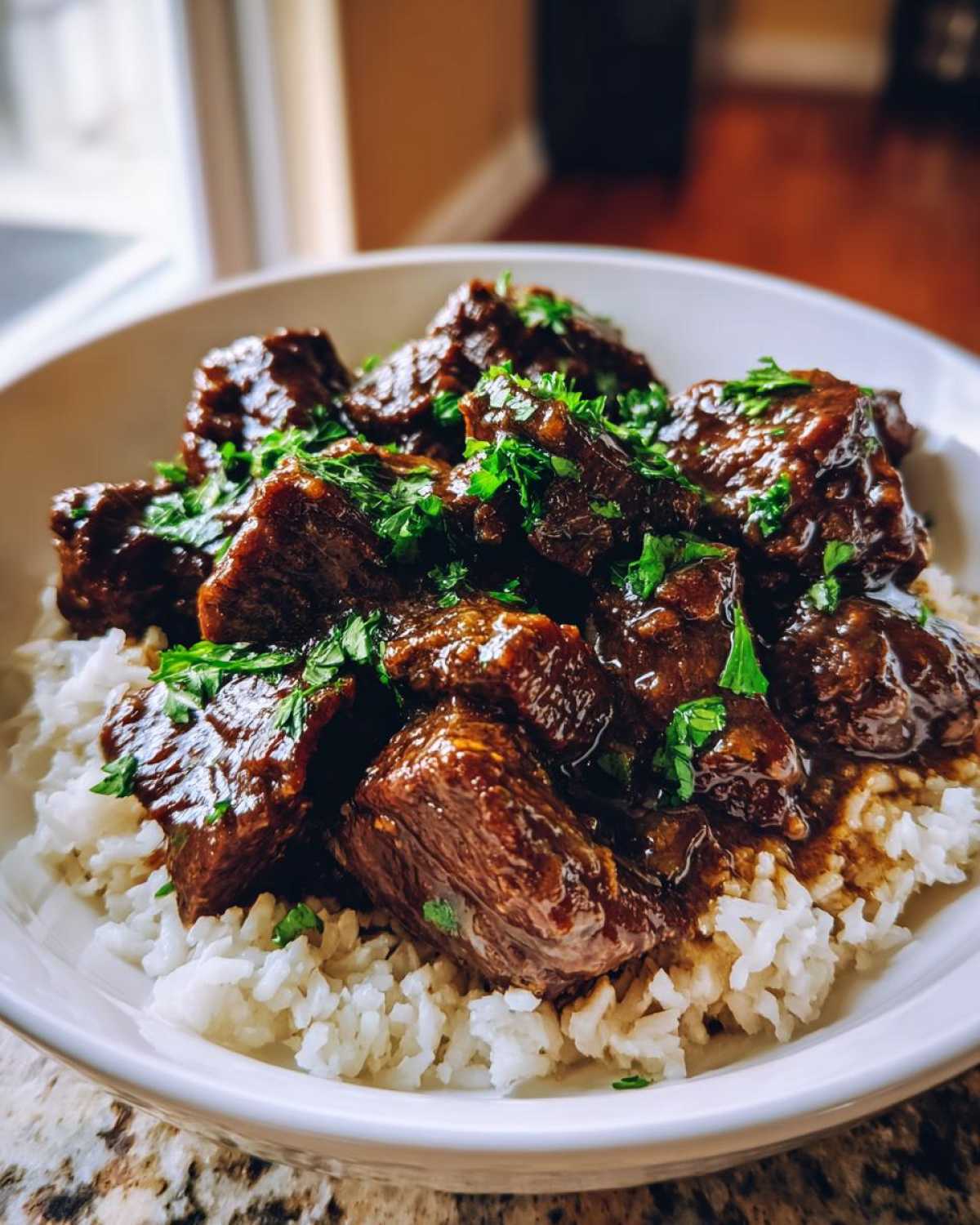 Close-up of tender crockpot steak chunks in rich sauce served over fluffy white rice and garnished with parsley.